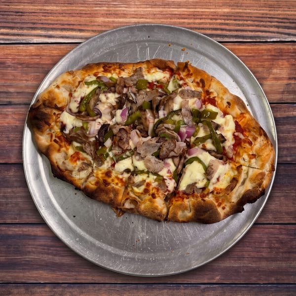 A freshly baked pizza with green peppers, red onions, and meat on a metal pan.